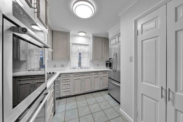 kitchen with sink, light tile patterned floors, ornamental molding, stainless steel appliances, and decorative backsplash