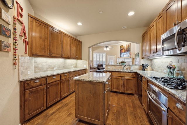 kitchen featuring light stone counters, dark wood-type flooring, a center island, and appliances with stainless steel finishes