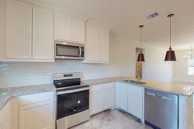 kitchen featuring sink, backsplash, stainless steel appliances, decorative light fixtures, and kitchen peninsula