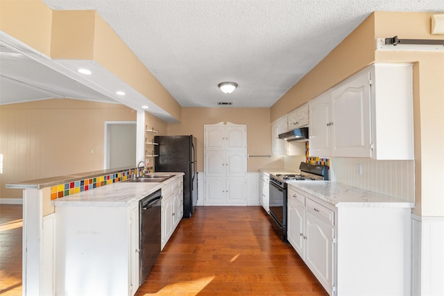 kitchen with black appliances, white cabinetry, hardwood / wood-style flooring, kitchen peninsula, and a textured ceiling