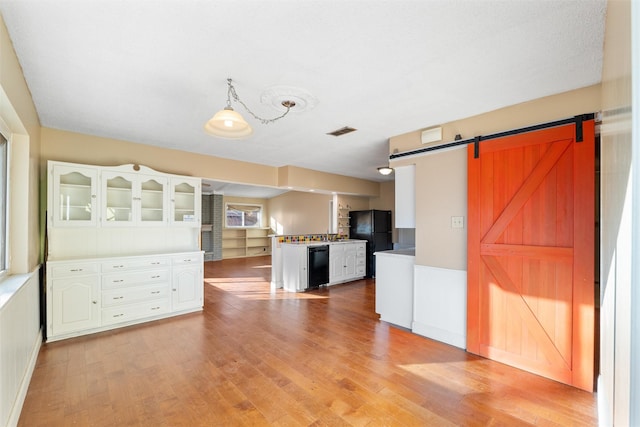 kitchen featuring black appliances, a barn door, and white cabinets