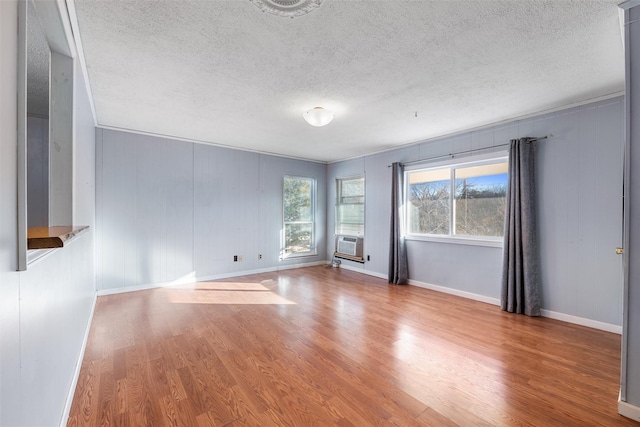 empty room with hardwood / wood-style flooring, cooling unit, and a textured ceiling