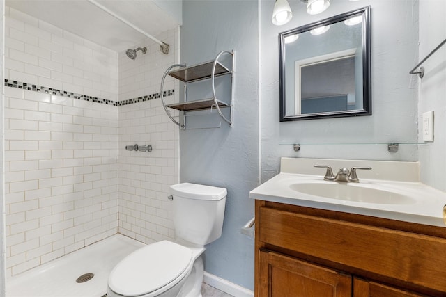 bathroom with vanity, toilet, and tiled shower