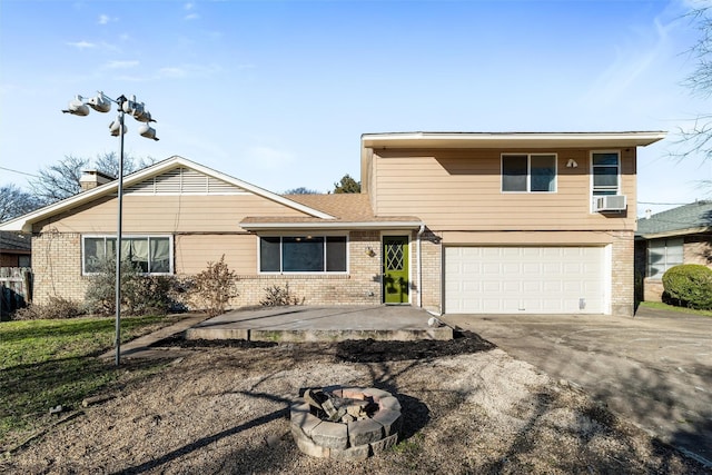 view of front facade featuring cooling unit, a garage, and an outdoor fire pit