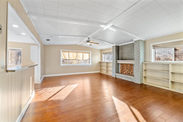 unfurnished living room featuring wooden walls, lofted ceiling with beams, light hardwood / wood-style flooring, a brick fireplace, and built in shelves