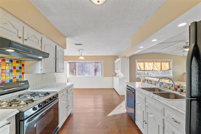 kitchen featuring dishwasher, sink, white cabinets, black fridge, and gas range oven