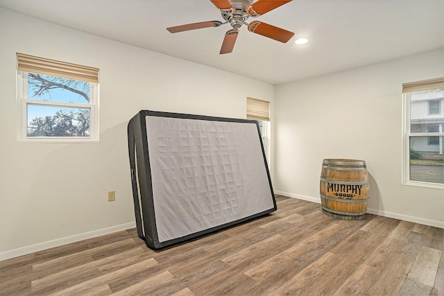 unfurnished bedroom featuring multiple windows, hardwood / wood-style floors, and ceiling fan