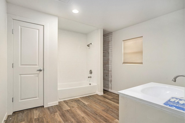 bathroom with hardwood / wood-style flooring, tiled shower / bath, and sink