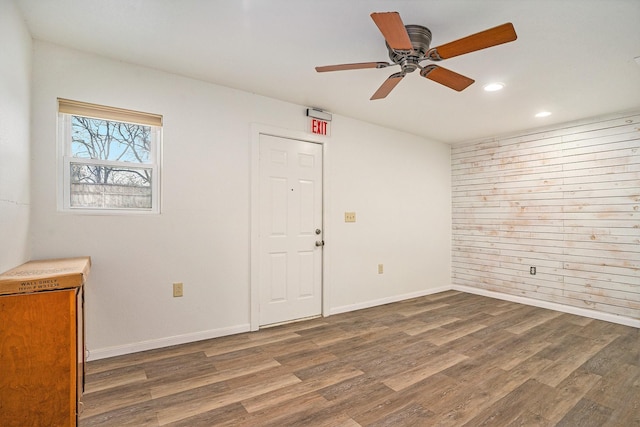 spare room with ceiling fan, wooden walls, and dark hardwood / wood-style flooring