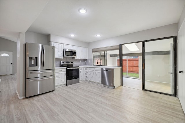 kitchen with sink, white cabinetry, stainless steel appliances, decorative backsplash, and light wood-type flooring