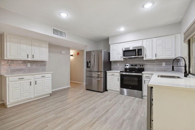 kitchen featuring white cabinetry, appliances with stainless steel finishes, light hardwood / wood-style floors, and sink