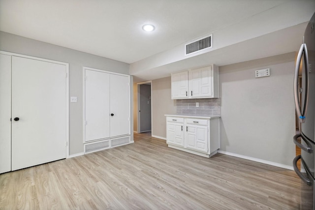 kitchen featuring tasteful backsplash, white cabinetry, stainless steel fridge, and light wood-type flooring