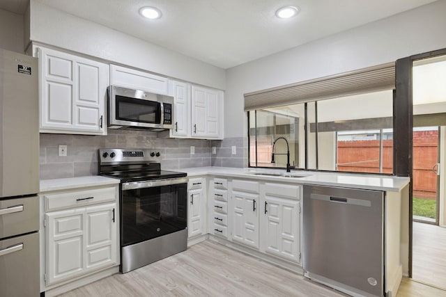 kitchen with white cabinetry, stainless steel appliances, sink, and tasteful backsplash