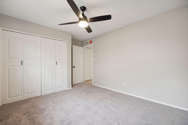 unfurnished bedroom featuring ceiling fan, a closet, and light carpet