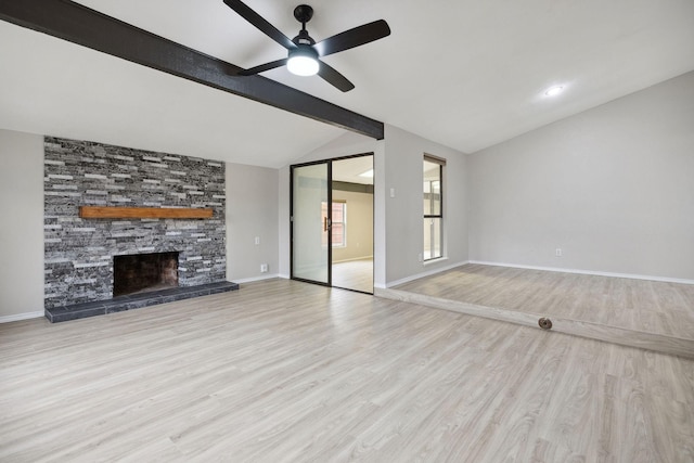 unfurnished living room featuring ceiling fan, a stone fireplace, lofted ceiling with beams, and light hardwood / wood-style flooring