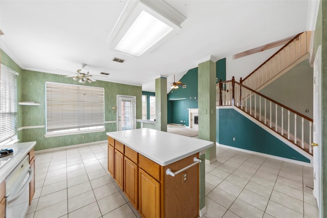 kitchen featuring light tile patterned floors, crown molding, a center island, and ceiling fan