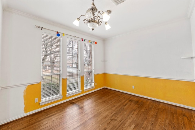 empty room featuring ornamental molding, wood-type flooring, and a chandelier