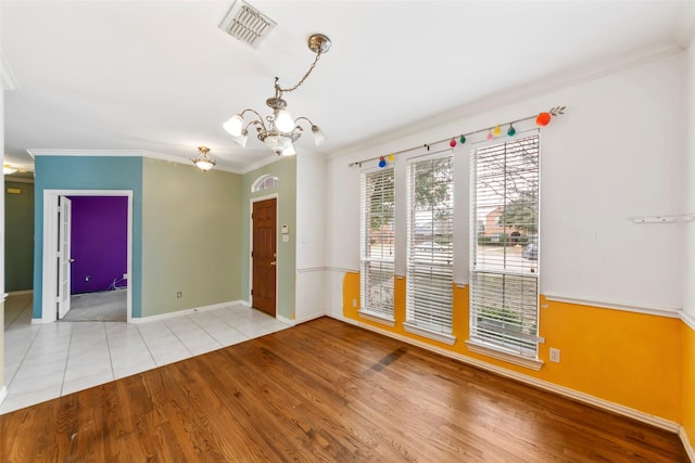 unfurnished room with crown molding, a chandelier, and light hardwood / wood-style flooring