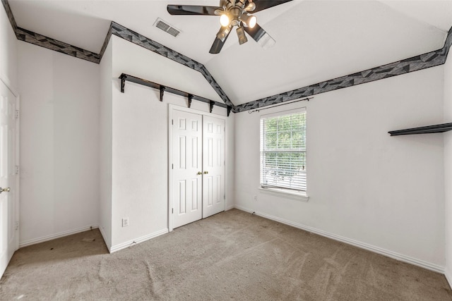 unfurnished bedroom featuring ceiling fan, light colored carpet, vaulted ceiling, and a closet