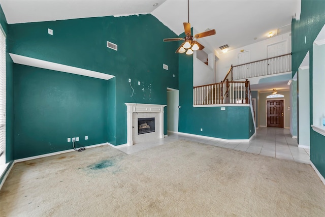 unfurnished living room with a tile fireplace, high vaulted ceiling, light colored carpet, and ceiling fan