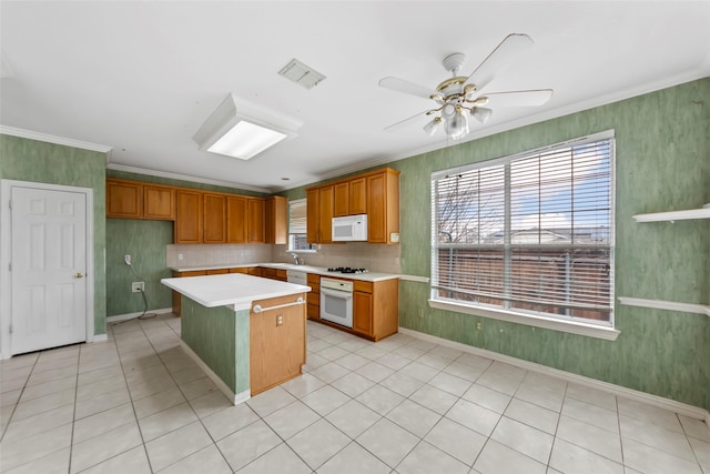 kitchen featuring white appliances, ornamental molding, a kitchen island, and plenty of natural light