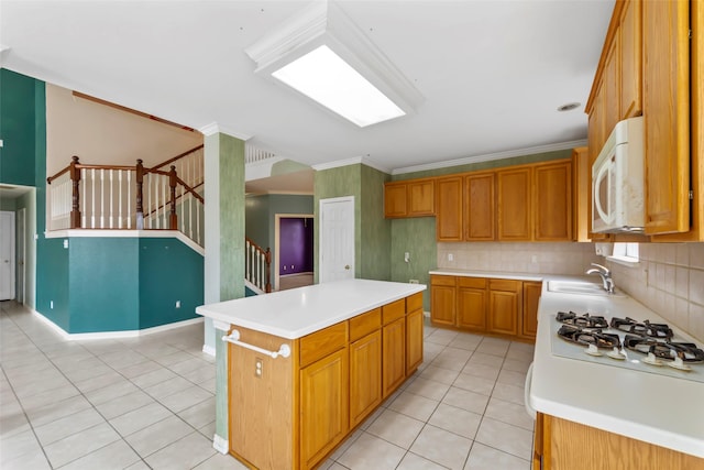 kitchen with sink, crown molding, white appliances, tasteful backsplash, and a kitchen island