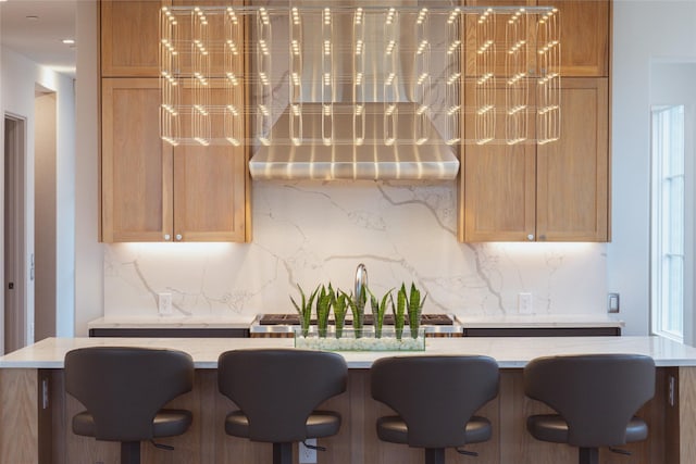 kitchen with tasteful backsplash, sink, light brown cabinets, and a kitchen breakfast bar