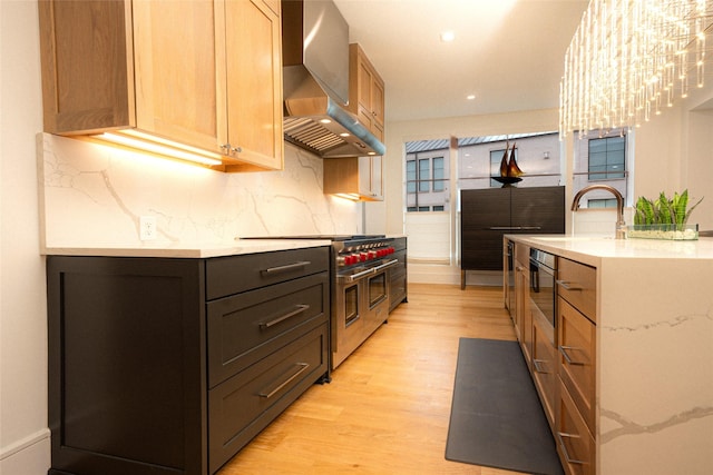 kitchen featuring sink, double oven range, tasteful backsplash, wall chimney exhaust hood, and light wood-type flooring