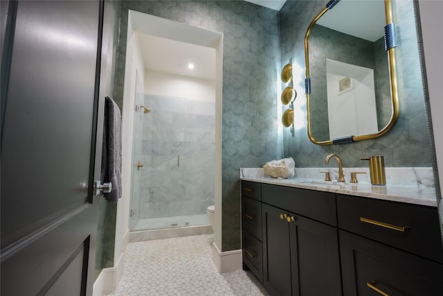 bathroom with tile patterned flooring, vanity, a tile shower, and toilet