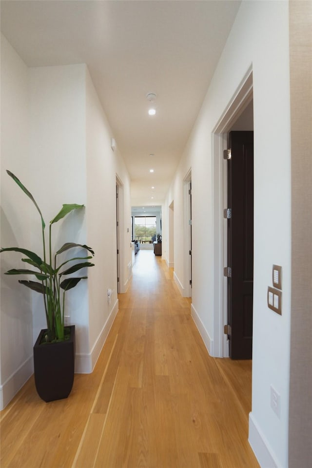 hallway with recessed lighting, light wood-style floors, and baseboards