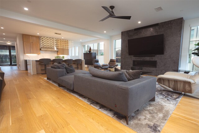 living room with ceiling fan, a fireplace, and light wood-type flooring