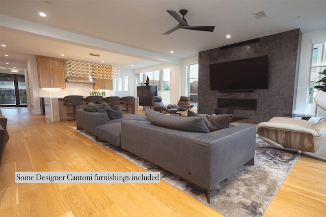living room featuring light wood-type flooring, visible vents, recessed lighting, a ceiling fan, and a fireplace