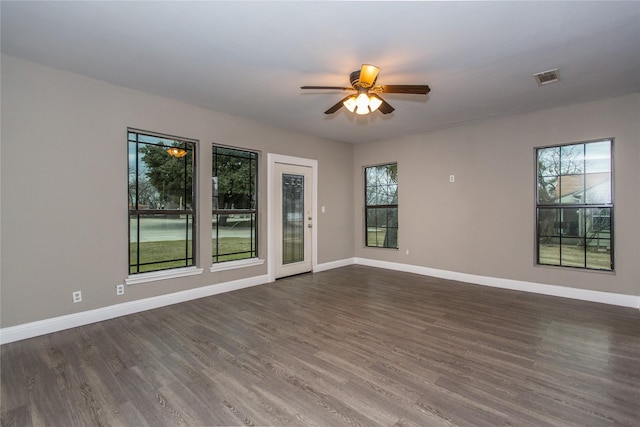 unfurnished room featuring plenty of natural light, dark wood finished floors, visible vents, and baseboards