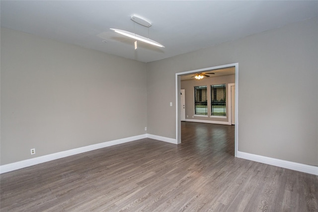 unfurnished room featuring ceiling fan, wood finished floors, and baseboards