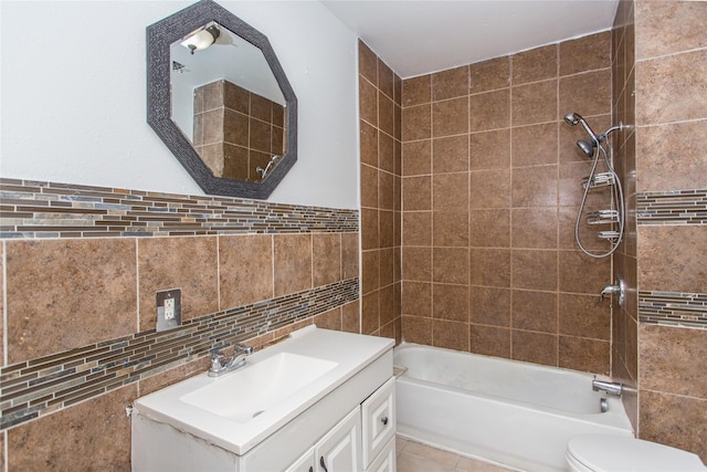 full bathroom featuring toilet, tile walls, vanity, tiled shower / bath combo, and tile patterned flooring