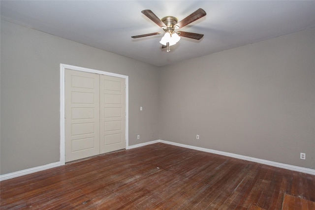 unfurnished bedroom with dark wood-style floors, ceiling fan, a closet, and baseboards