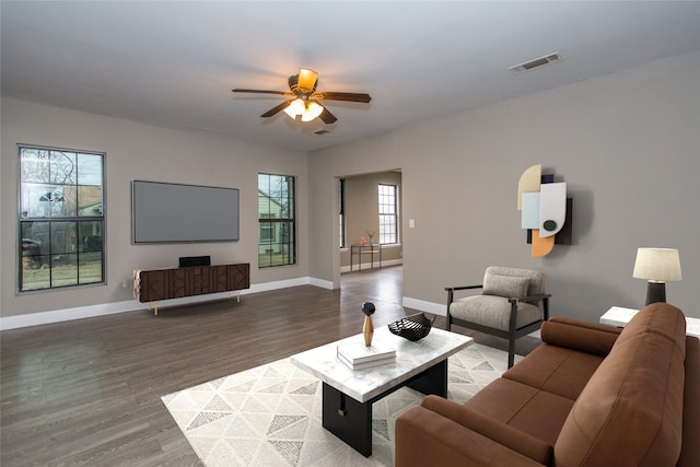 living room featuring visible vents, ceiling fan, baseboards, and wood finished floors