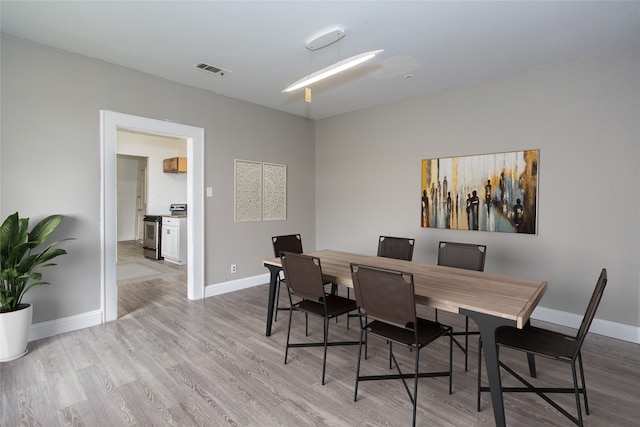 dining space with light wood finished floors, baseboards, and visible vents