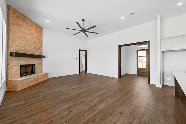 unfurnished living room featuring dark hardwood / wood-style floors, ceiling fan, and a fireplace