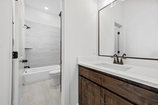 full bathroom featuring vanity, tiled shower / bath, and toilet