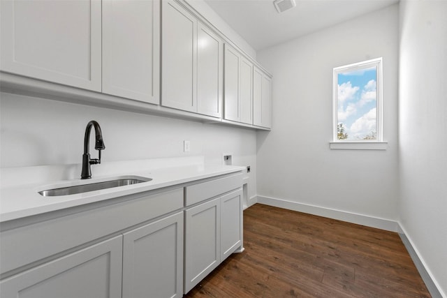 washroom featuring cabinets, electric dryer hookup, sink, and dark hardwood / wood-style floors