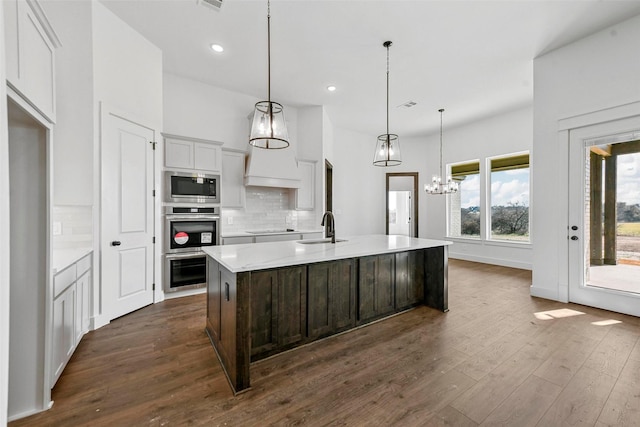 kitchen featuring sink, decorative light fixtures, a center island with sink, appliances with stainless steel finishes, and backsplash