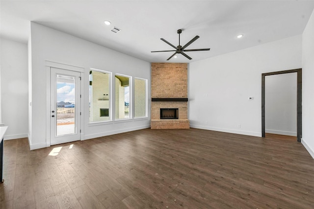 unfurnished living room with a large fireplace, dark hardwood / wood-style floors, and ceiling fan