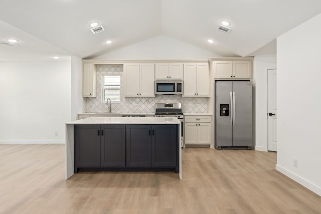 kitchen with decorative backsplash, vaulted ceiling, stainless steel appliances, and a kitchen island