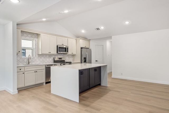 kitchen featuring stainless steel appliances, white cabinetry, a center island, and sink