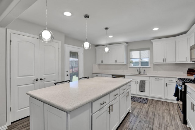 kitchen with a center island, decorative light fixtures, stainless steel gas range, and white cabinets