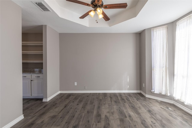 unfurnished room featuring dark hardwood / wood-style flooring, a raised ceiling, and ceiling fan