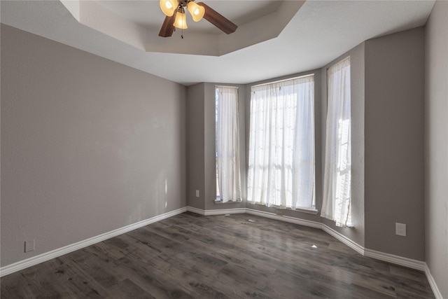 spare room featuring dark wood-type flooring, ceiling fan, and a tray ceiling