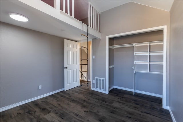 unfurnished bedroom with lofted ceiling, dark wood-type flooring, and a closet