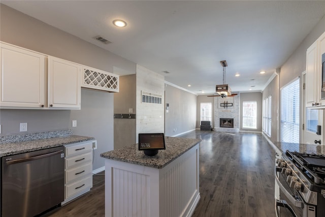 kitchen with light stone counters, a center island, white cabinets, and appliances with stainless steel finishes